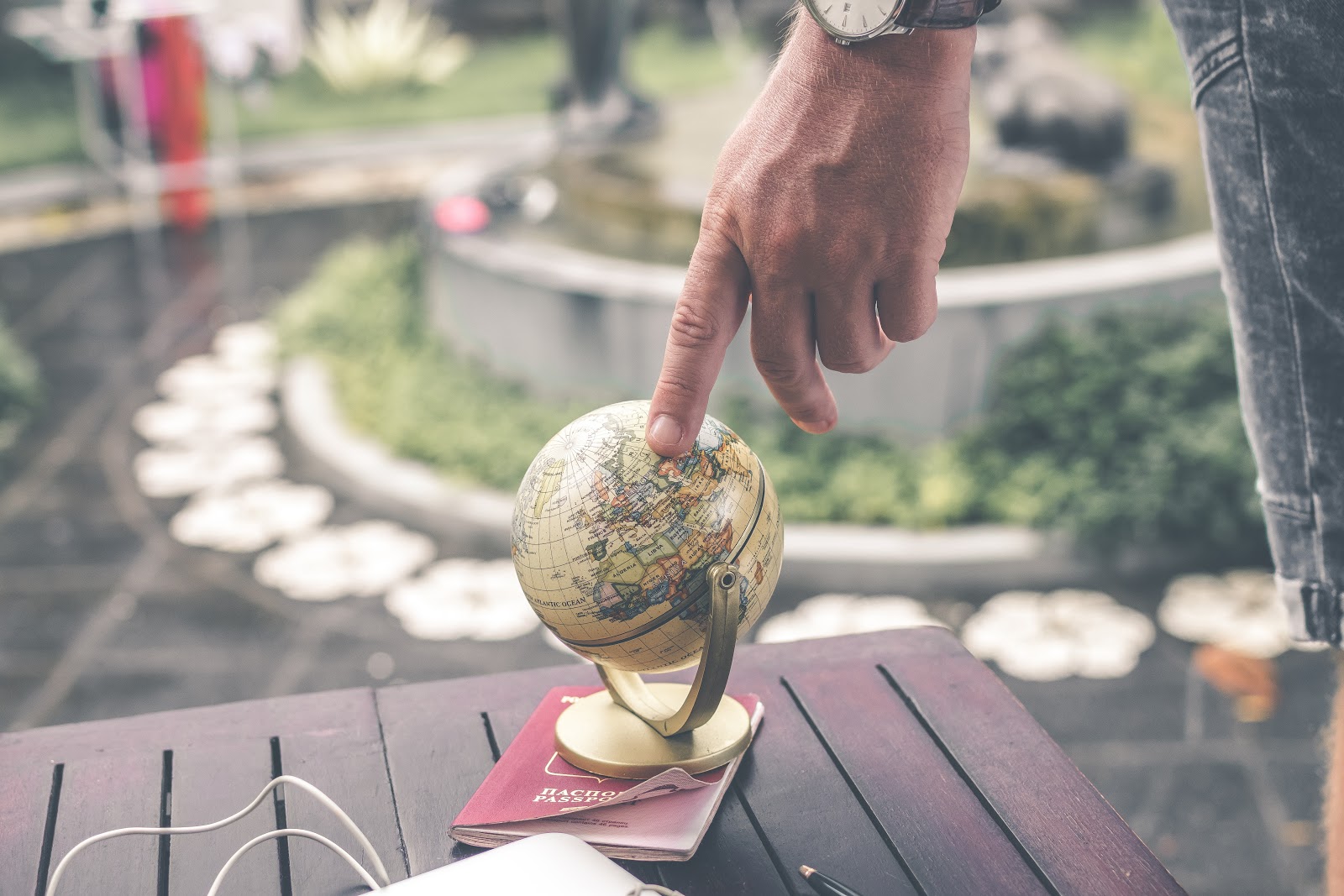 A finger pointing to a small globe. Learning how to speak a language can make the world a lot smaller!