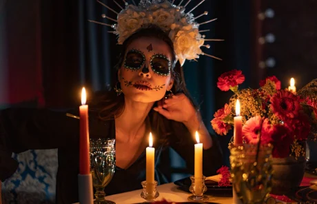 A woman with a painted face celebrating Day of the Dead with candles