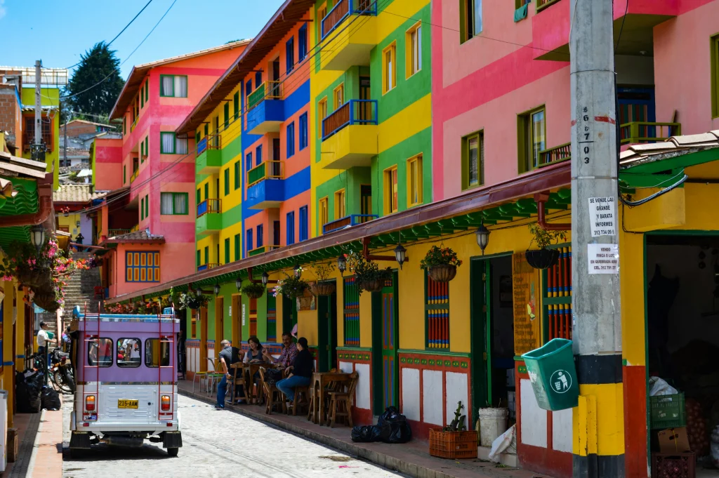 A picture of colorful houses with people hanging out outside in a Colombian city. 