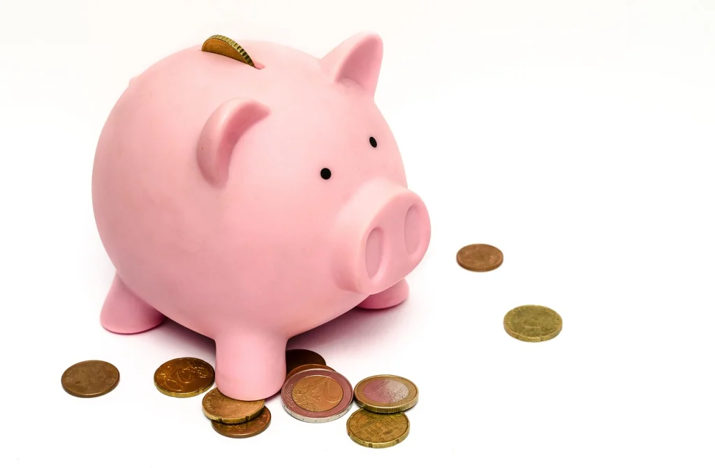 A pink piggy bank with coins around it