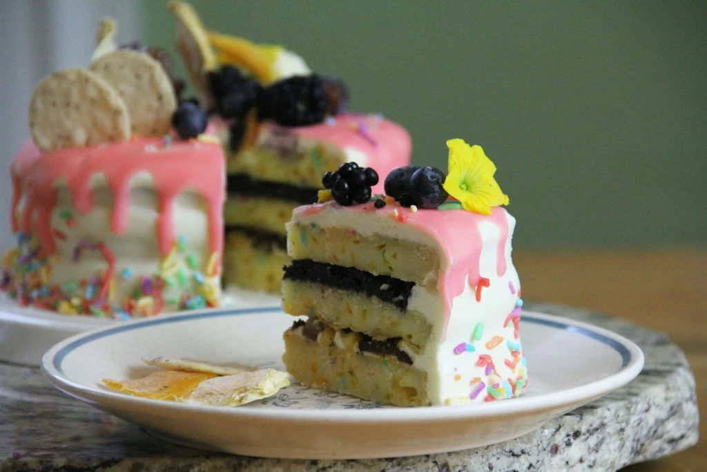 A slice of cake on a ceramic plate is placed before a pink frosted cake.